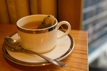 Close up of a fresh cup of hot herbal tea with a tea bag in a white ceramic mug.