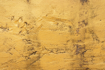 Rough textured yellow surface with visible dark imperfections and trowel marks