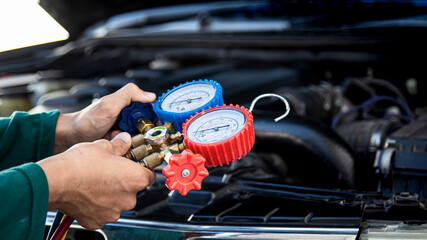 Mechanic checking car ac refrigerant with manifold gauge set