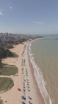PRAIA DE CABO BRANCO, VISTA LINDA COM VARIOS PREDIOS E QUARDA SOL E UM MAR LINDO COM ONDAS (Cabo Branco Beach, beautiful view with various buildings and umbrellas and a beautiful sea with waves.)