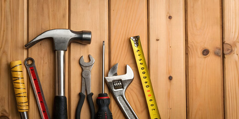 Tools on wood background, hammer, wrench, screwdriver, pliers, tape measure