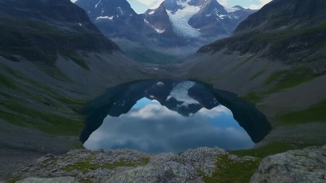 4K slow motion aerial footage of glacial cirque lake revealed from high vantage drift