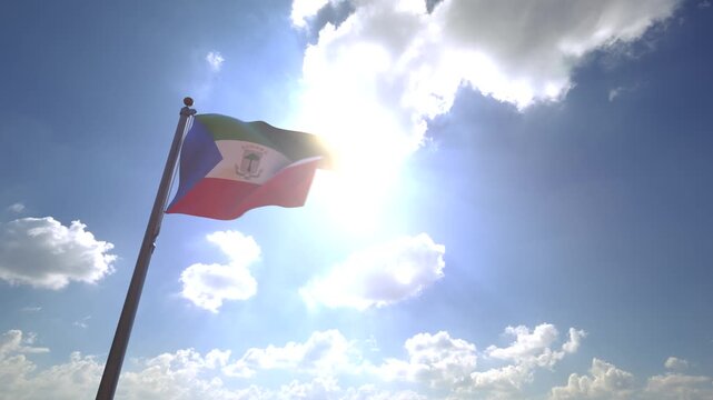 Equatorial Guinea Flag waving on a Flagpole from a Moving Angle in front of a blue sky with clouds	