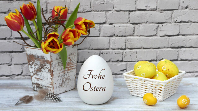 Frohe Ostern: Blumenstrau&szlig; mit Ostereiern vor einer Steinmauer.