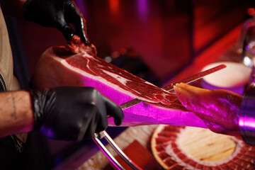 Chef slicing traditional Spanish jamon with black gloves