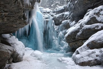 Waterfall cascading through icy rock formations in a snow-covered landscape