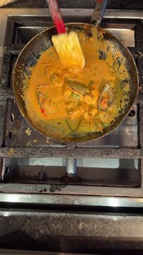 Cooking of Creamy Coconut Seafood Curry Sauce with King Prawns Shrimps and Whole Mussels in Shells in a Pan