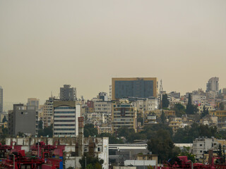 Naklejka premium Urban view of Beirut, Lebanon with dense residential buildings spreading across the hills and mountains, photographed from the industrial port area.