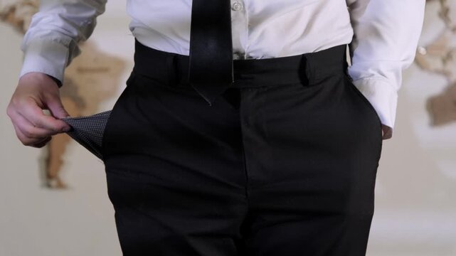 Businessman showing empty trouser pockets without money standing in office