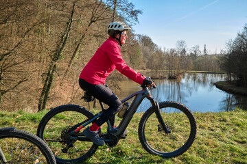 Obraz premium active senior woman cycling with her electric mountain bike on a warm sunny spring day in the Swabian Forest, in Badeb.Woerttemberg, Germany