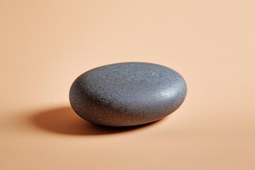 A smooth, rounded black stone resting on a warm peach background, symbolizing tranquility and natural beauty.