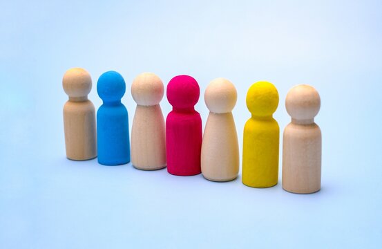 Colorful wooden peg dolls in a row on a blue background. A concept for diversity, inclusion, leadership and team dynamics