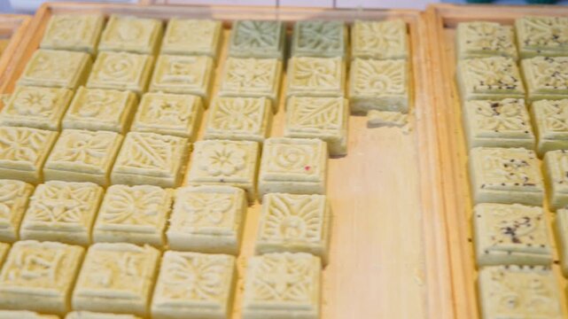 Rows of delicately pressed traditional Chinese peanut candies featuring intricate patterns, ready for sale at a vibrant night market in Shanghai, offering a taste of local culture, China, Asia