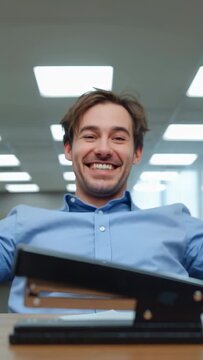Vertical video: Reacting to surprise man in blue shirt pressing stapler smiling in office