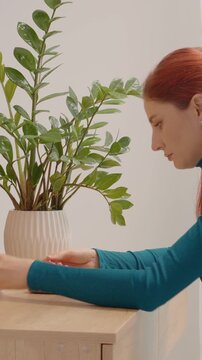 Vertical Screen: A woman sits at a table and takes a blood sugar test using a glucometer. She puts the test strip into the device to check her glucose level.