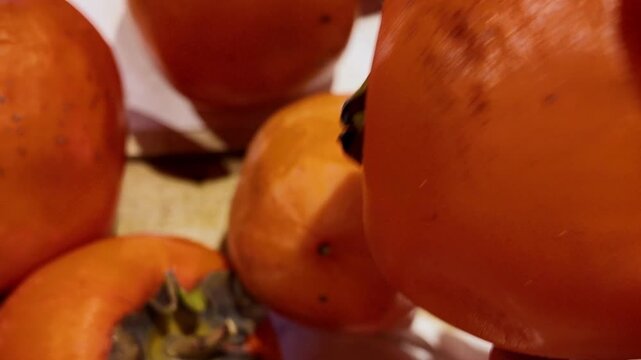 A customer chooses in a supermarket ripe juicy persimmon fruits