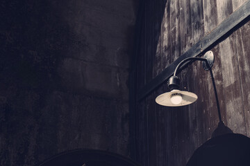 木の扉とレトロな外灯を備えた暗い雰囲気の建物外観 