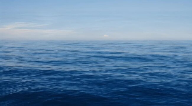 Vast, calm blue ocean water under a pale blue sky with distant clouds