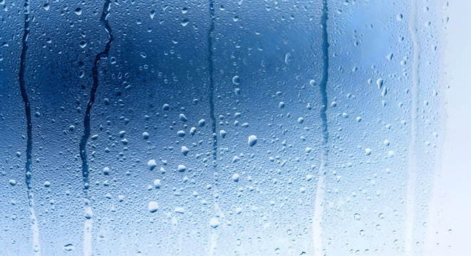 A close-up view of a wet glass surface with water droplets and a blue background