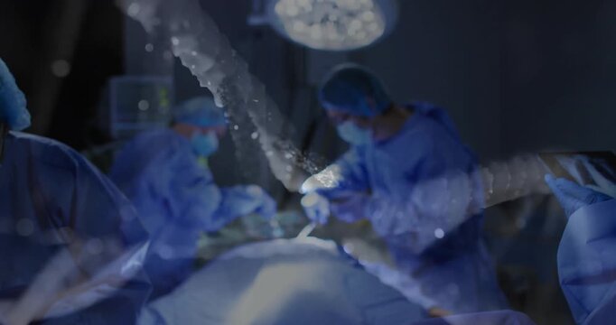 Medical team performing surgery under overhead surgical light, showing animated tablet data overlay