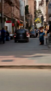 Vertical video: Driving yellow rickshaw man in shirt steering along city street flags fluttering