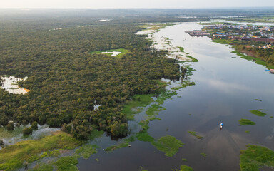Naklejka premium High-resolution aerial drone view of the riverside community of Barrio de Belén in Iquitos, showing houses built along flooded wetlands and a traditional boat navigating through the water channels
