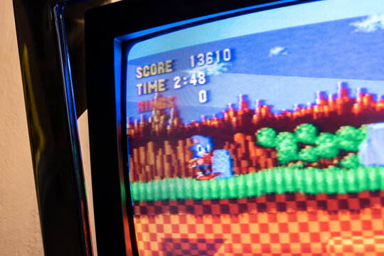Sonic the Hedgehog game on vintage CRT television, extreme closeup of pixel art gameplay with score HUD and scanlines on curved glass screen, nostalgic retro console gaming concept, no people