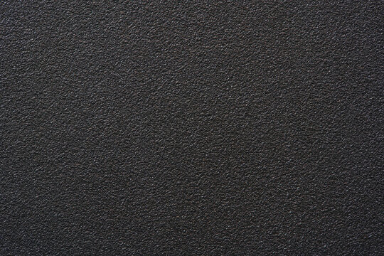 Black textured plastic surface background full frame top view of rough matte electronics casing material, dark abstract backdrop wallpaper technology design template, high resolution detail, no people