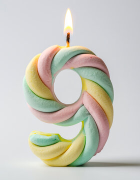 Close-up view of a pastel glossy candle shaped as the number six with lit flame on gray backdrop