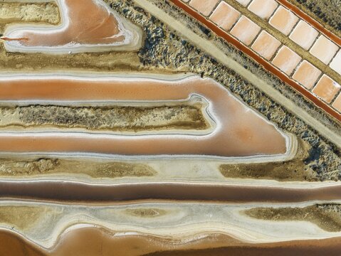 Saline ponds at the salt works near Chiclana de la Frontera. The orange-red colour depends on the level of salinity and is directly caused by the algae Dunaliella salina and brine shrimp. Aerial view. Drone shot. C&aacute;diz province, Andalusia, Spain