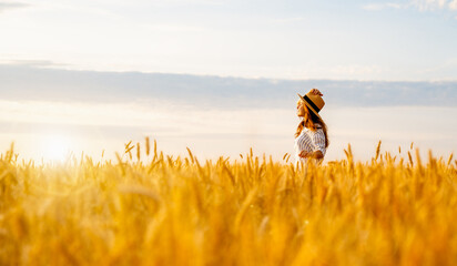 Young woman standing in agricultural field enjoying rural landscape. Agritourism lifestyle.