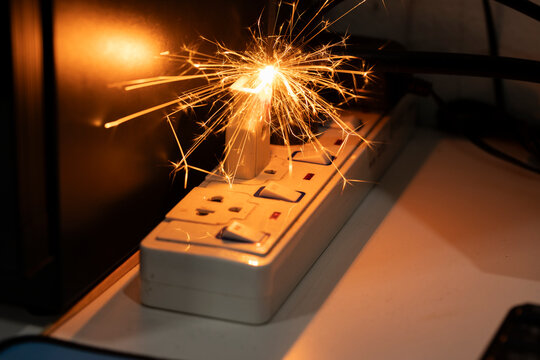Electrical short circuit with sparks in a power strip. Overloaded socket fire hazard concept. Danger of electricity at home, faulty wiring and domestic accident prevention Filming in the studio