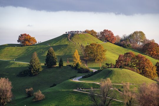 Autumnal trees in the Olympic Park, people at the lookout mountain Olympiaberg, view from the Olympic Stadium, Olympic Park, Munich, Bavaria, Germany