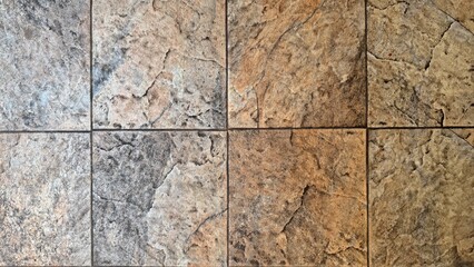 Obraz premium Top-down view of textured beige and grey ceramic floor tiles mimicking natural stone clefts.