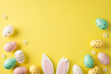 Obraz premium Happy Easter flat lay featuring pastel painted eggs, bunny ears and small daisies arranged on a bright yellow background for spring holiday inspiration