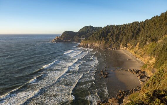 Sandy beach Sealion Beach with Devils Elbow, in the back rocky coast with Heceta Head lighthouse, Oregon, USA