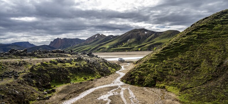 Car driving through landscape near Landmannalaugar, Dramatic volcanic landscape, Colourful erosion landscape with mountains, Lava field, Landmannalaugar, Fjallabak Nature Reserve, Su&eth;urland, Iceland