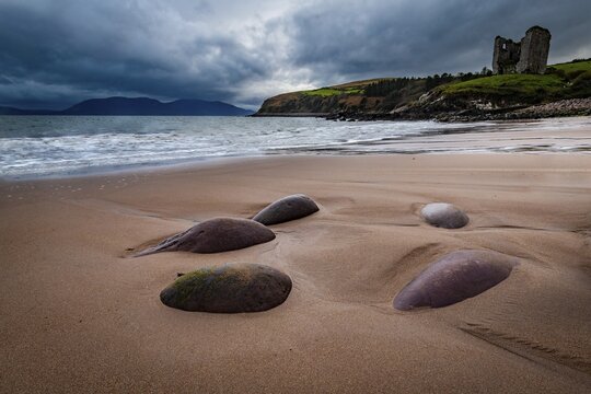 Sandy beach beach with stones and Minard Castle in the background, Dingle Peninsula, Kerry, Ireland