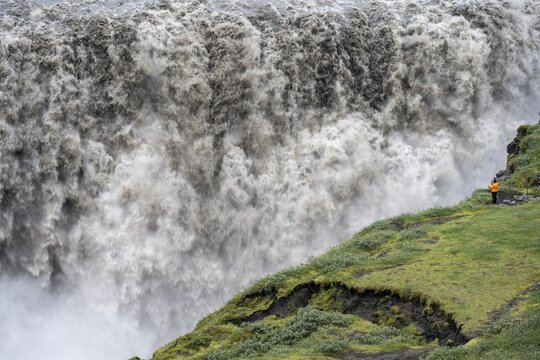 Man at the edge of a canyon, canyon with falling water masses, Dettifoss waterfall in summer, North Iceland, Iceland
