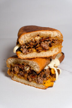 Stacked halves of classic Philly cheesesteak sandwich with tender beef peppers and melted cheese