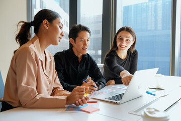 Diverse team collaborating on a laptop during a business meeting in a modern office