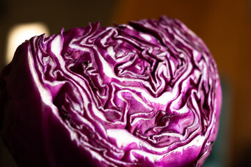 Close-up of a halved red cabbage showcasing its vibrant purple colour and intricate leaf patterns. The texture is detailed and fresh, ideal for culinary themes.