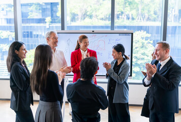 Fototapeta premium Diverse business team applauds success during a modern office meeting with whiteboard presentation