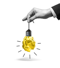 Fototapeta premium Hand of businessman holding a light bulb made of crumpled paper by its cord.