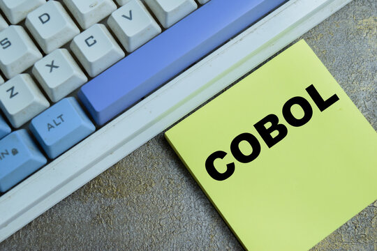 Concept of COBOL - Common-Business Oriented Language programming write on sticky notes isolated on Wooden Table. For legacy system maintenance, maintenance technology, banking software development