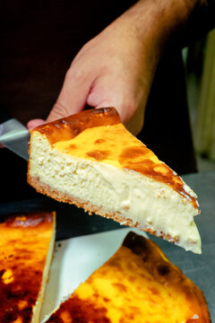 Close up of a slice of creamy basque cheesecake being served on a plate with soft texture and golden top