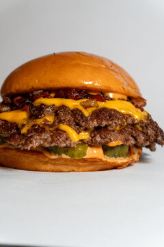 Massive double cheeseburger with multiple patties melted cheese and pickles on white background