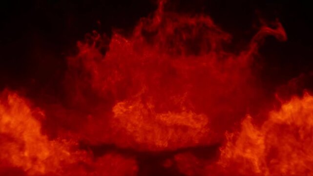 Wide shot of a raging wall of intense red fire and turbulent flames against a solid black background
