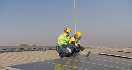 Professional engineers are inspecting solar panels on a rooftop using a laptop and tablet, focusing...