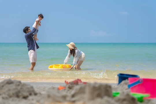 Multigenerational Asian family enjoying summer beach vacation, playing and relaxing together.